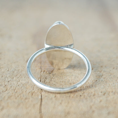 back view of a Silver ring with a white stone on a wooden surface