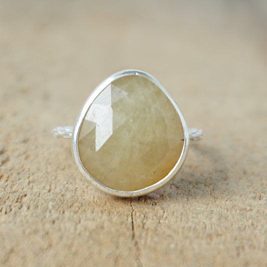 silver ring with a tan stone on a wooden background