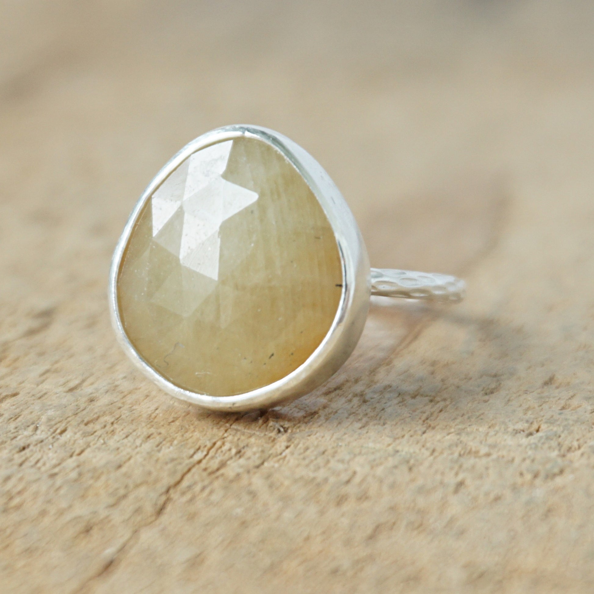 silver ring with a tan stone on a wooden background