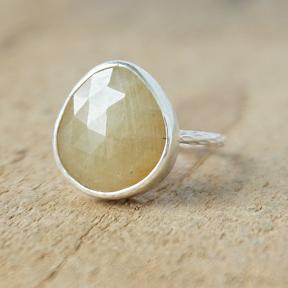 silver ring with a tan stone on a wooden background