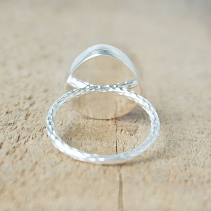 back view of a silver ring with a tan stone on a wooden background