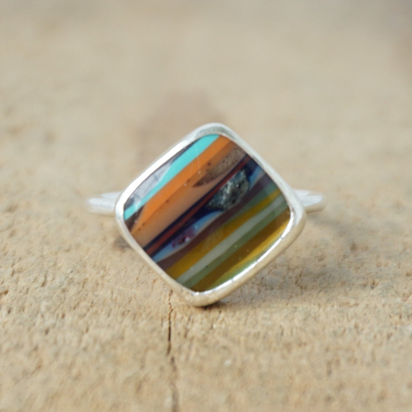 silver ring with a striped stone on a wooden background