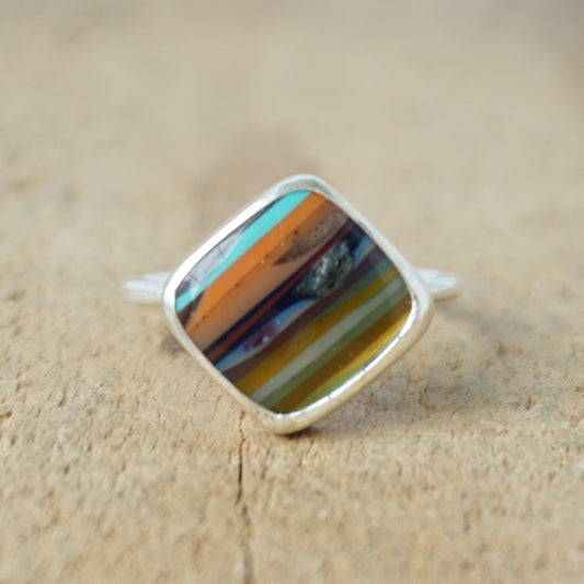 silver ring with a striped stone on a wooden background