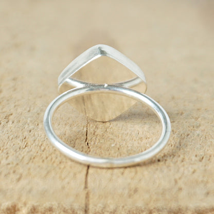 back view of a silver ring with a striped stone on a wooden background