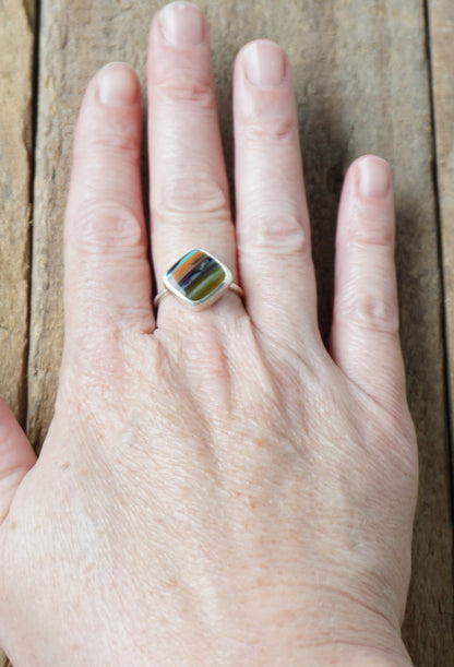 silver ring with a striped stone on a wooden background