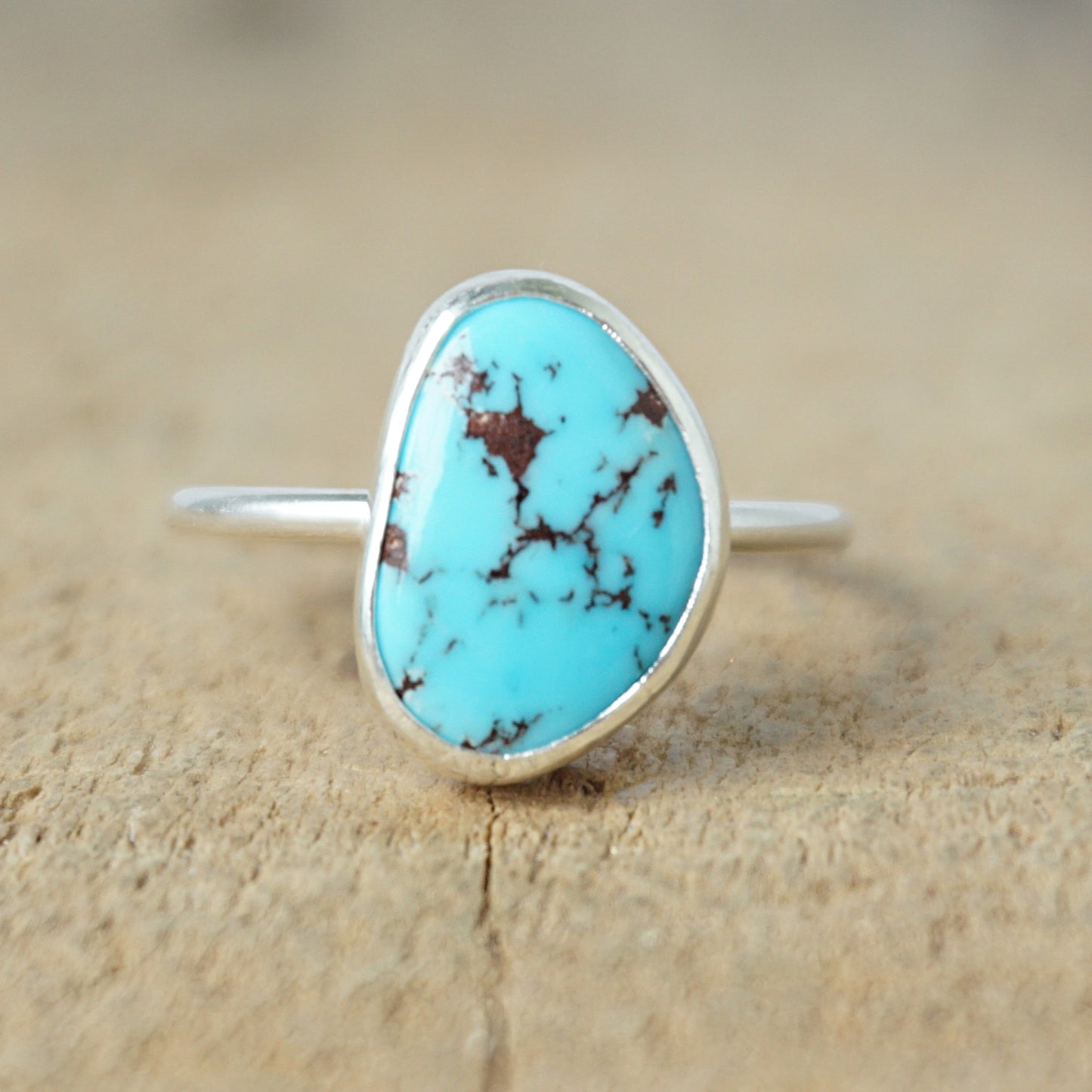 Turquoise ring with silver band on a wooden surface