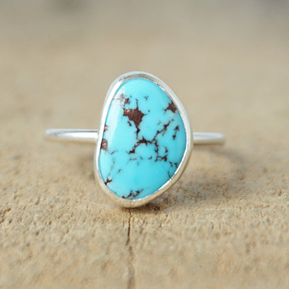 Turquoise ring with silver band on a wooden surface