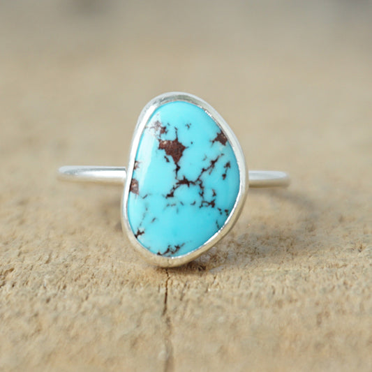 Turquoise ring with silver band on a wooden surface