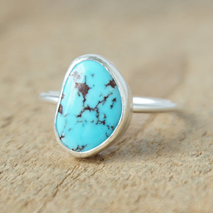 Turquoise ring with silver band on a wooden surface