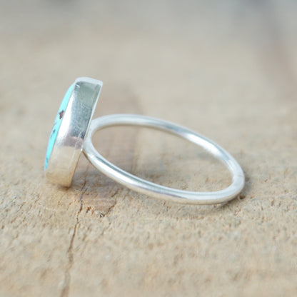 side view of a Turquoise ring with silver band on a wooden surface