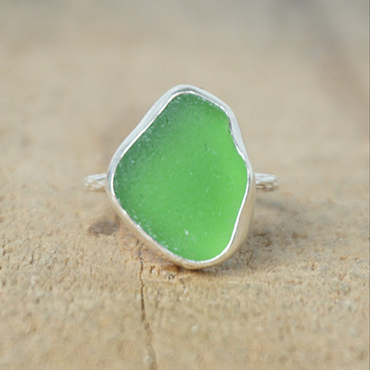 silver ring with green sea glass on a wooden background