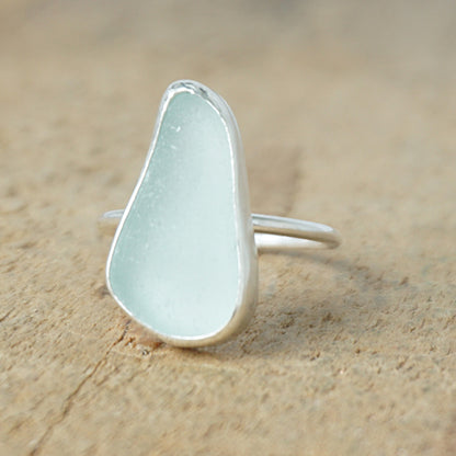light aqua blue sea glass ring with a sterling silver setting, against a wooden background