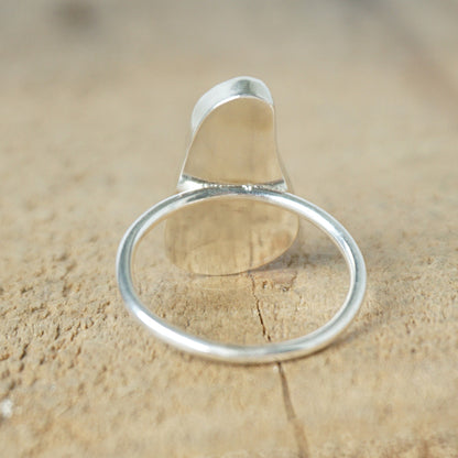 back view of a light aqua blue sea glass ring with a sterling silver setting, against a wooden background