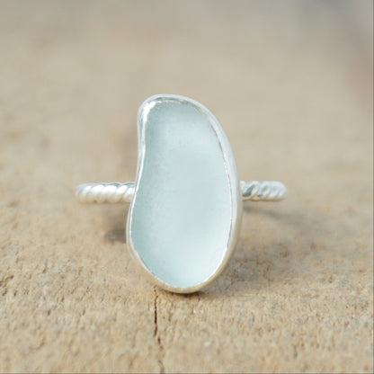 light aqua blue sea glass ring with a sterling silver setting, against a wooden background