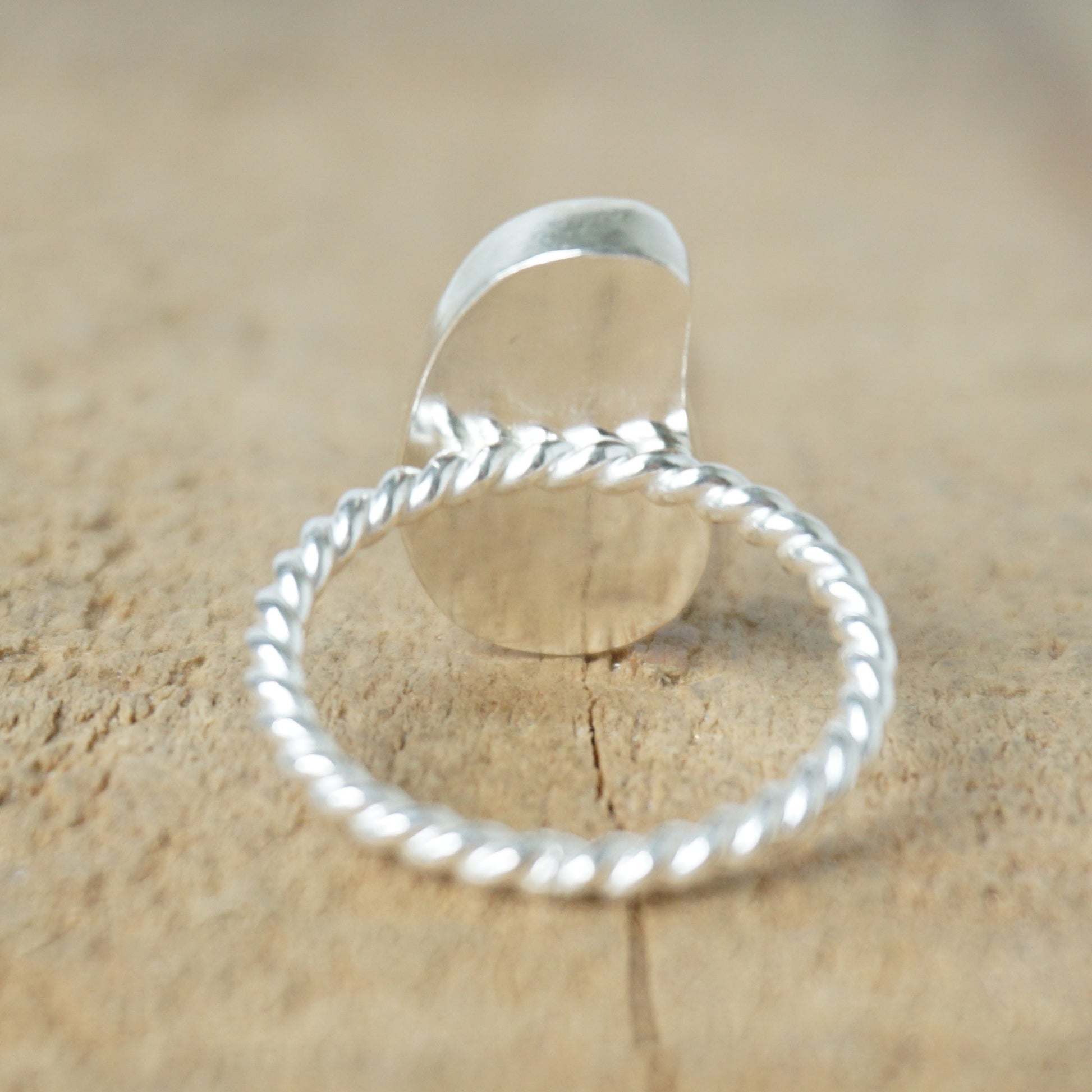 back view of a light aqua blue sea glass ring with a sterling silver setting, against a wooden background