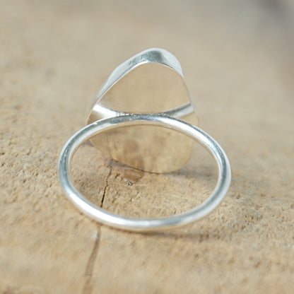 back view of a light aqua blue sea glass ring with a sterling silver setting, against a wooden background