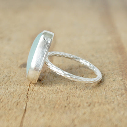 side view of a light aqua blue sea glass ring with a sterling silver setting, against a wooden background