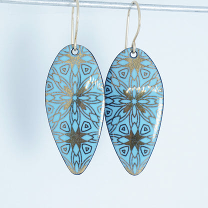 gold pattern on light blue enamel teardrop shaped earrings, on a white background