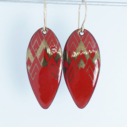 gold pattern on red enamel teardrop shaped earrings, on a white background