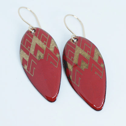 gold pattern on red enamel teardrop shaped earrings, on a white background
