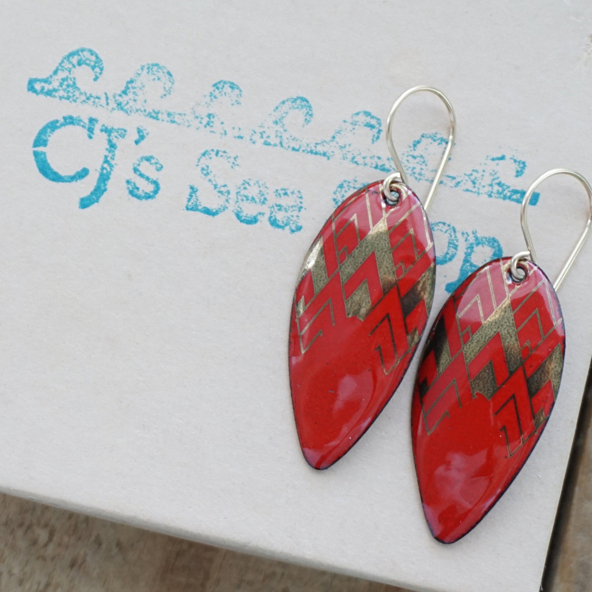 gold pattern on red enamel teardrop shaped earrings, on a gift box