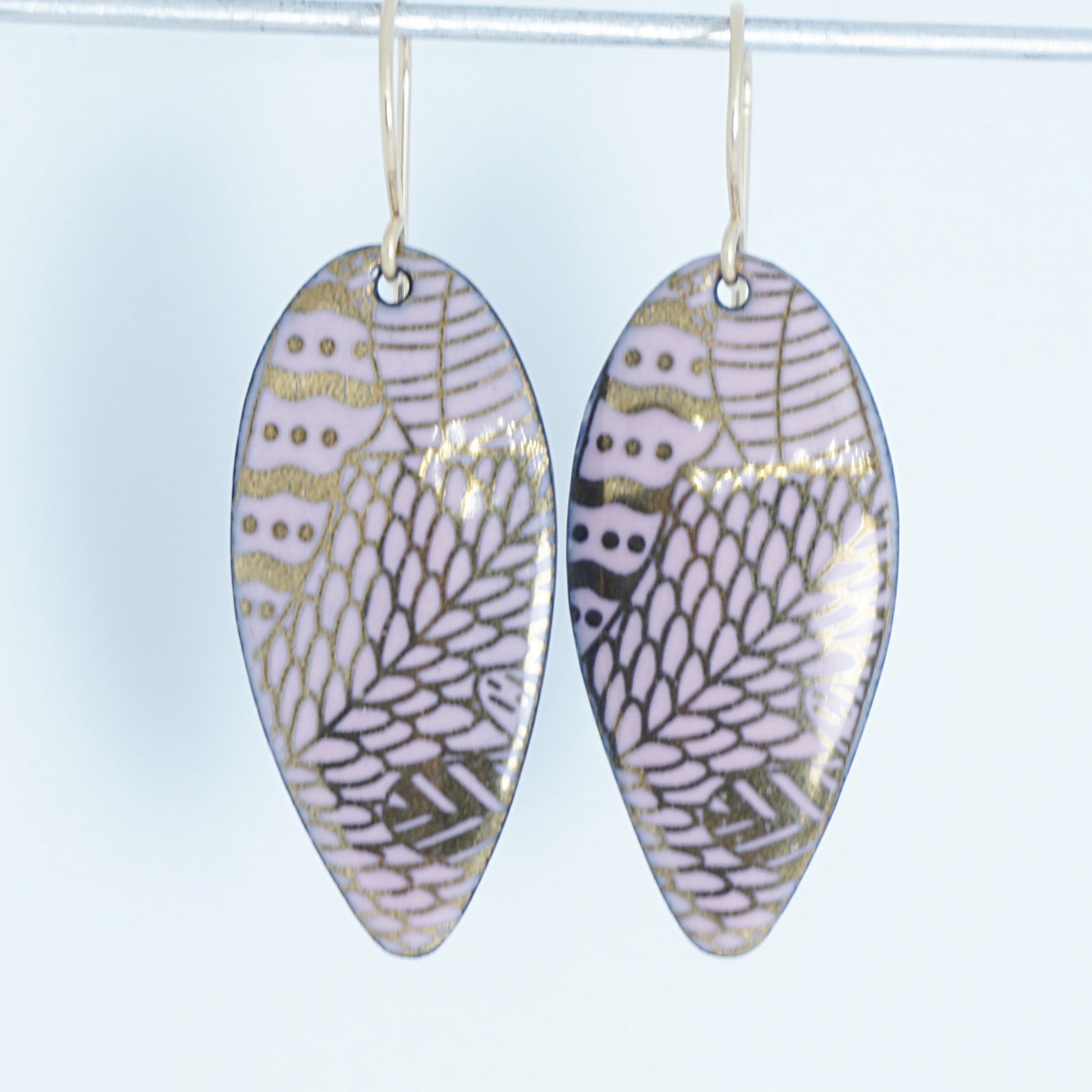 gold pattern on pink enamel teardrop shaped earrings, on a white background