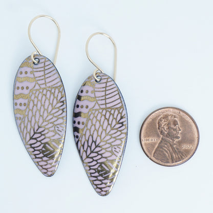 gold pattern on pink enamel teardrop shaped earrings, next to a penny for scale, on a white background