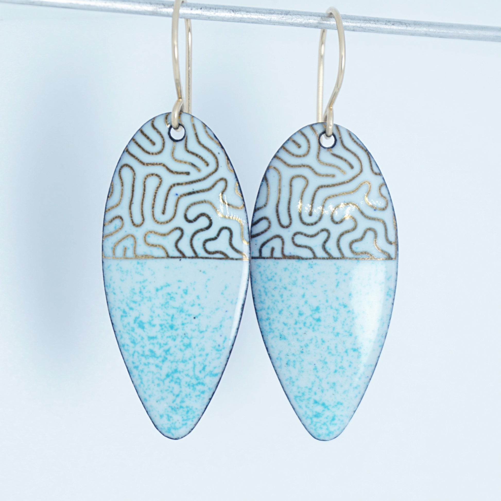 gold pattern on seafoam green enamel teardrop shaped earrings, on a white background