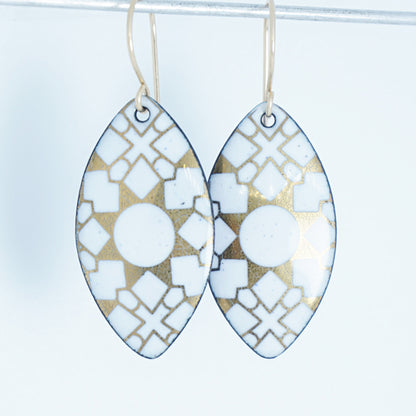 White, marquis shaped earrings with gold accents, against a white background