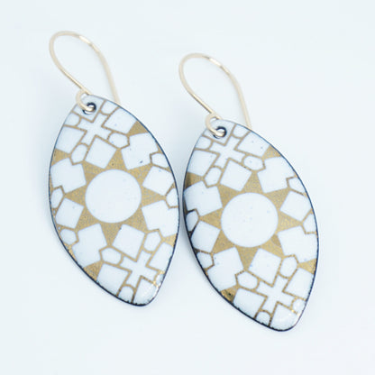 White, marquis shaped earrings with gold accents, against a white background