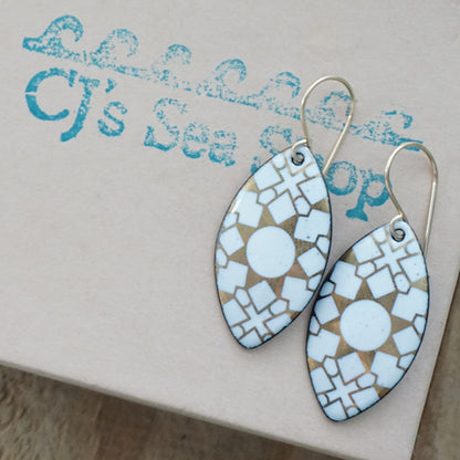 White, marquis shaped earrings with gold accents, on a gift box