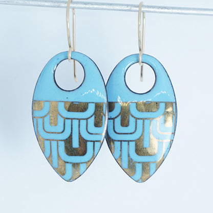 Light blue, teardrop shaped earrings with gold accents, against a white background