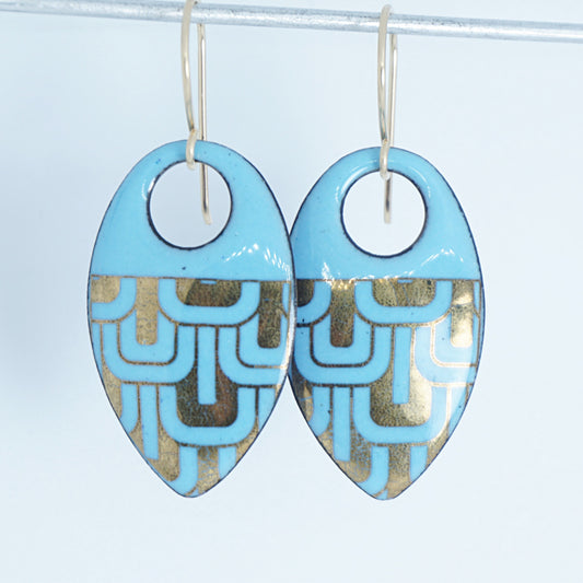 Light blue, teardrop shaped earrings with gold accents, against a white background