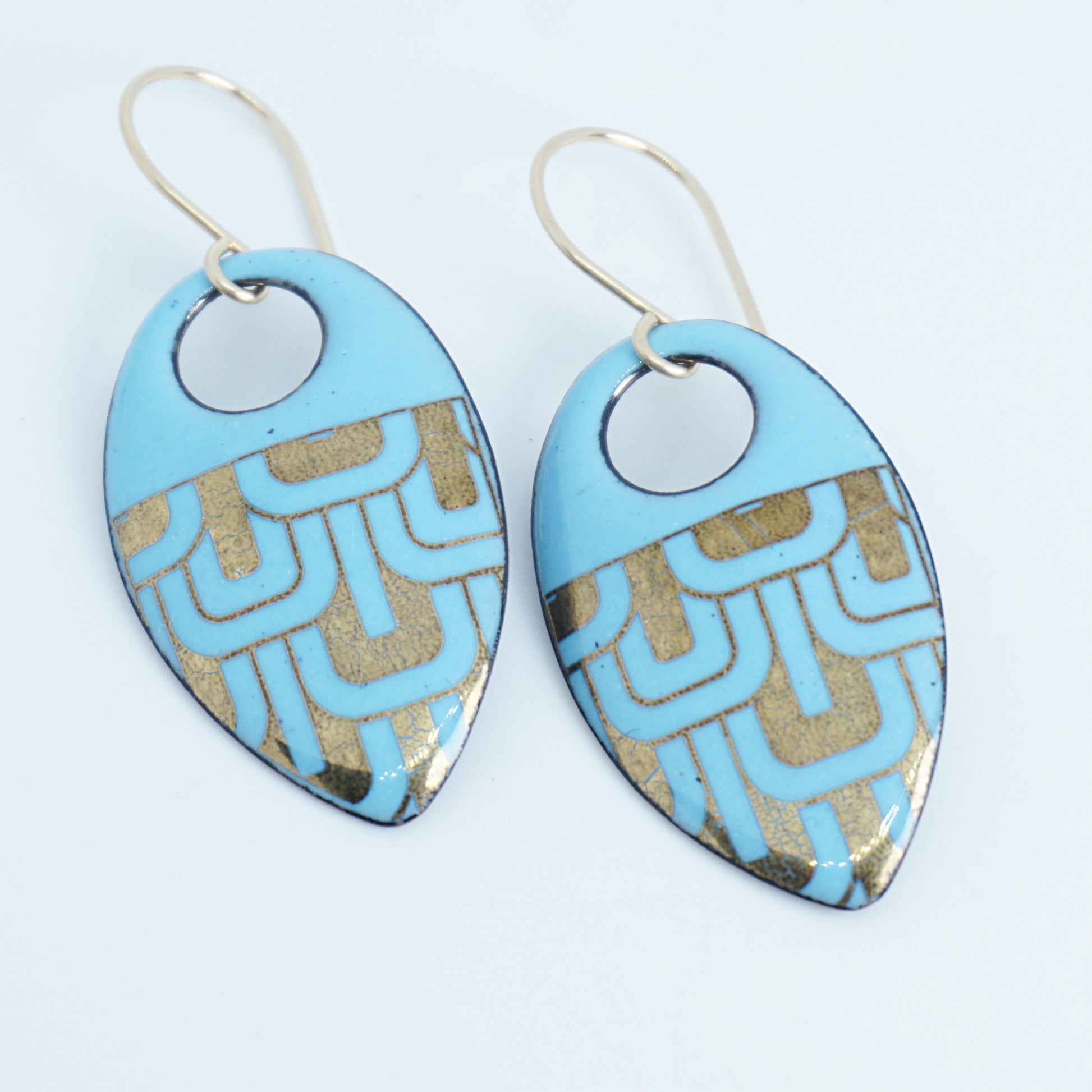 Light blue, teardrop shaped earrings with gold accents, against a white background