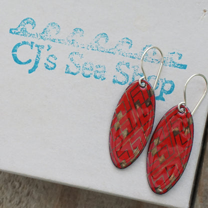 Red, oval shaped earrings with gold accents, on a gift box