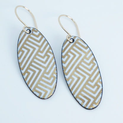 White, oval shaped earrings with gold accents, against a white background
