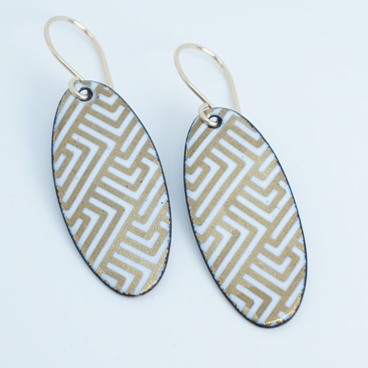 White, oval shaped earrings with gold accents, against a white background