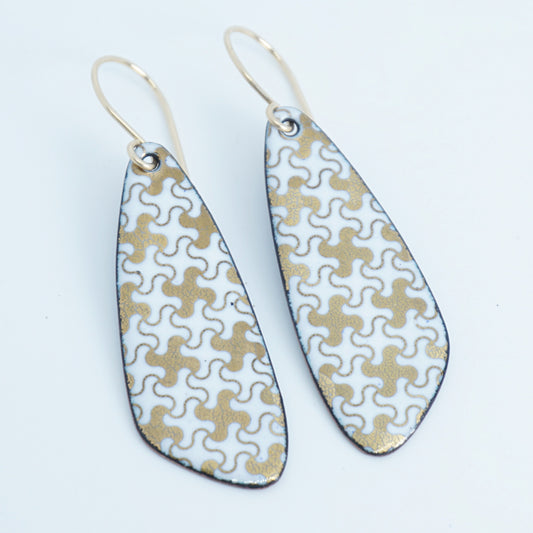 A pair of teardrop-shaped dangle earrings with a white and gold interlocking puzzle piece pattern, suspended from thin gold fishhook wires, shown on a plain white background.