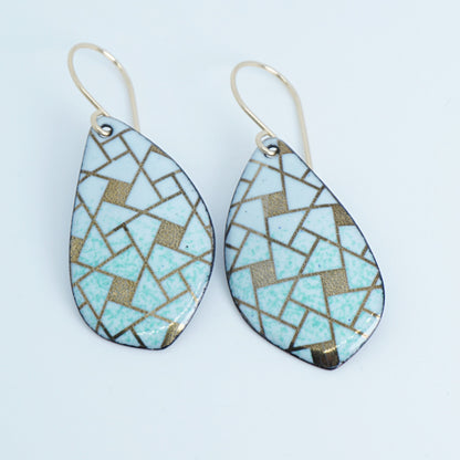A pair of leaf-shaped drop earrings with a mosaic pattern of light green and gold tiles, suspended from gold fishhook wires on a white background