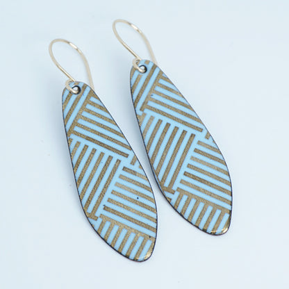 A pair of teardrop-shaped drop earrings with a light blue and gold geometric striped pattern, hanging from thin gold hooks on a white background.