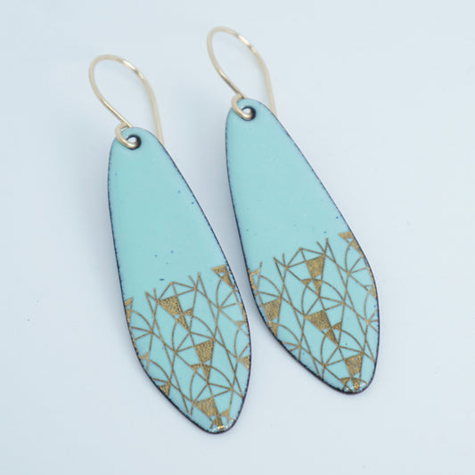 A pair of seafoam green teardrop shaped earrings with gold geometric accents, suspended from thin gold hooks on a white background