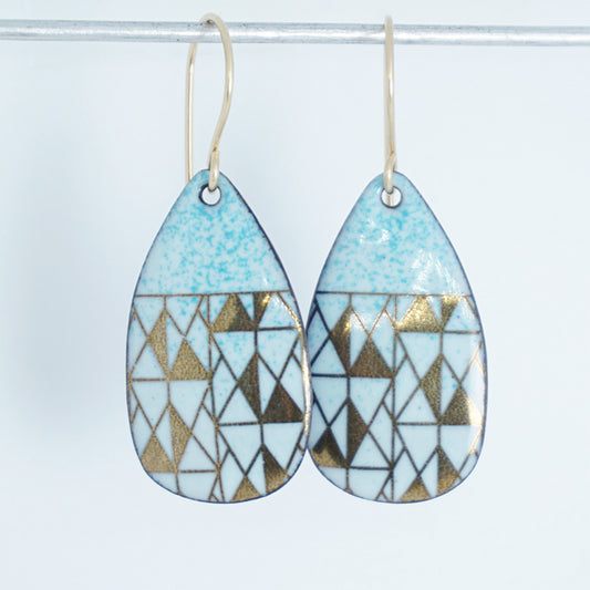 A pair of teardrop-shaped dangle earrings with seafoam green enamel and gold geometric pattern, against a white background