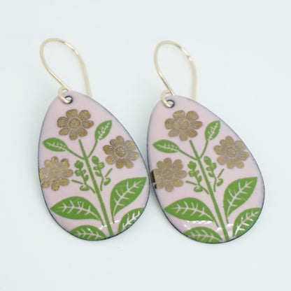 Pink teardrop-shaped dangle earrings, with gold flowers on green stems dangling from gold hooks, against a white background