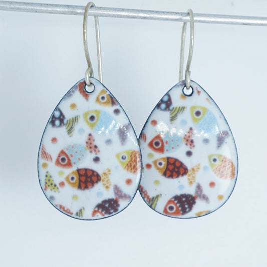 A pair of teardrop-shaped dangling earrings with a colorful fish pattern on a white background, hanging from silver hooks.