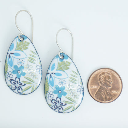 Teardrop-shaped dangle earrings with a blue, green, and white floral pattern, shown next to a US penny for scale on a white background.