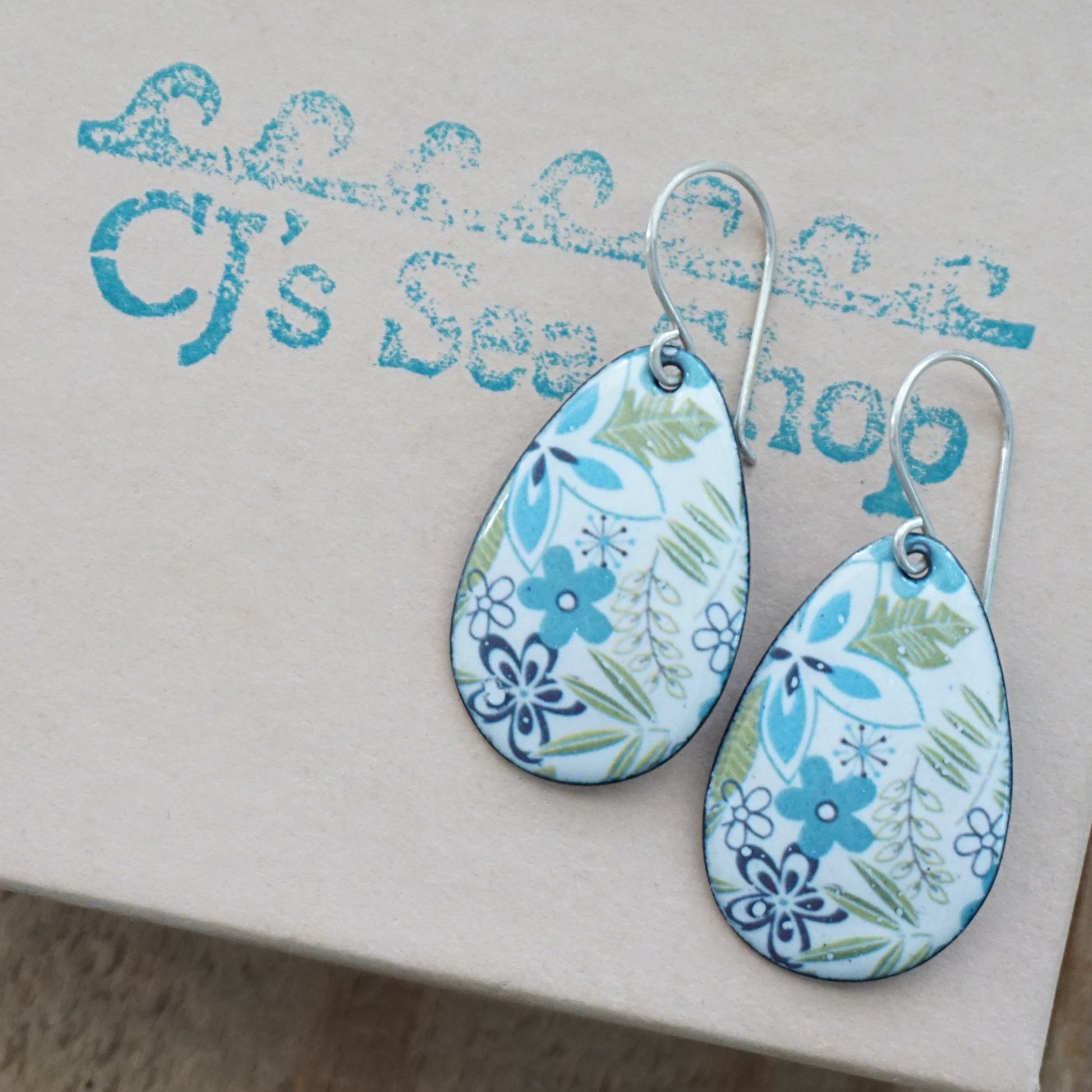 Teardrop-shaped earrings with a blue and green floral pattern on a white background, displayed on a gift box