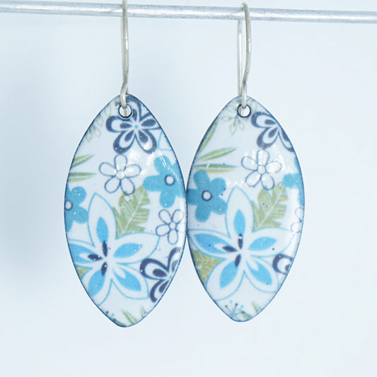 A pair of dangling marquise-shaped earrings with a white background and a purple, light blue, and green floral pattern, hanging from silver hooks against a white background.
