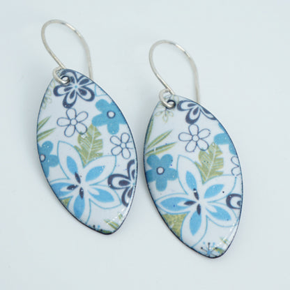 A pair of marquis-shaped dangling earrings with a white background and a blue, purple, and green floral pattern, suspended from silver fishhook wires on a white background.