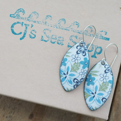Blue and white floral marquis shaped earrings with silver-toned wire hooks, displayed on a gift box