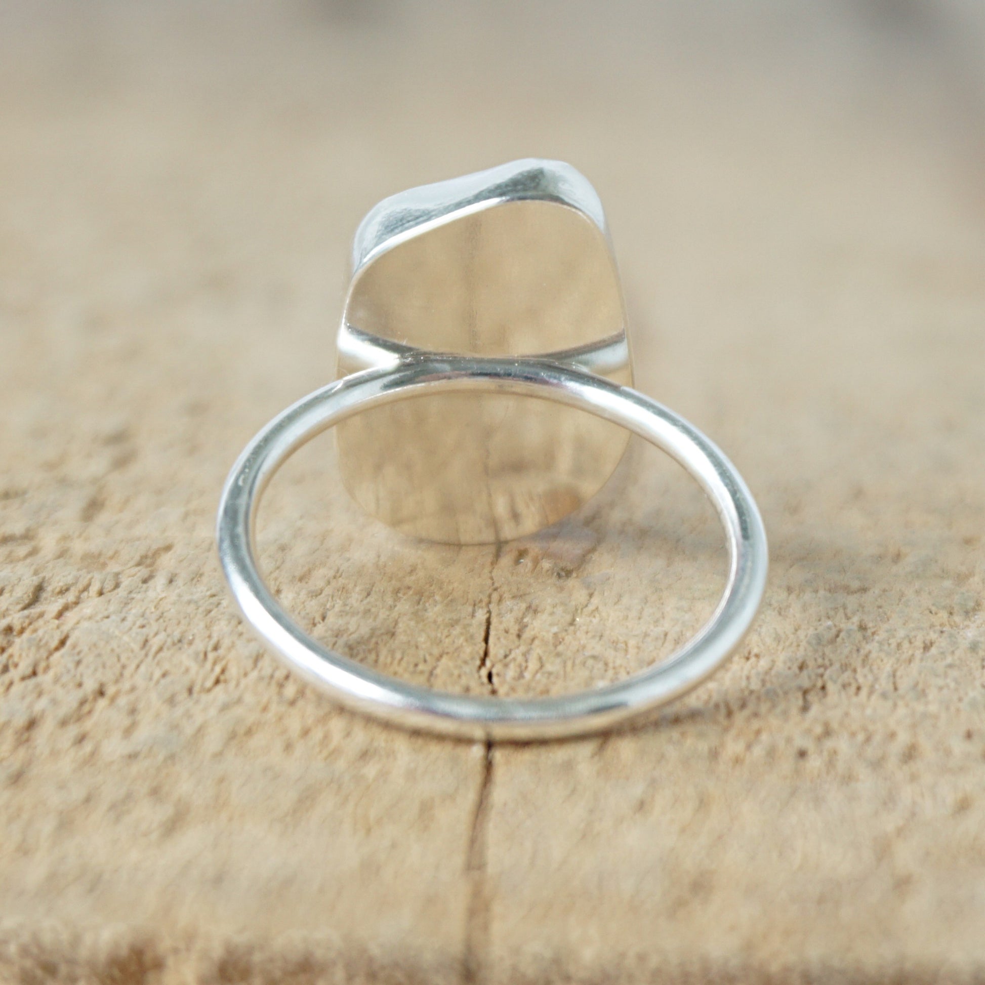 back view of a silver ring with cobalt blue sea glass, on a wooden surface.